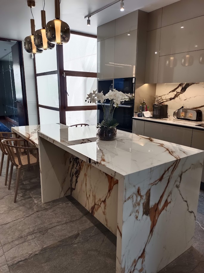 Sala moderna con sofá en L beige, sillones curvos y pared decorativa con papel tapiz geométrico en tonos grises