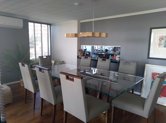 Sala moderna con sofá en L beige, sillones curvos y pared decorativa con papel tapiz geométrico en tonos grises
